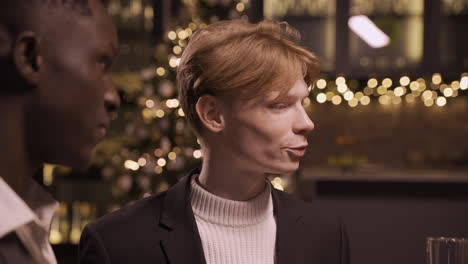 close up view of two friends wearing stylish clothes while talking and holding champagne glasses at new year's party