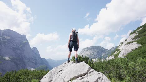 Female-hiker-standing-on-a-rock-looking-out-at-the-beautiful-mountain-landscape