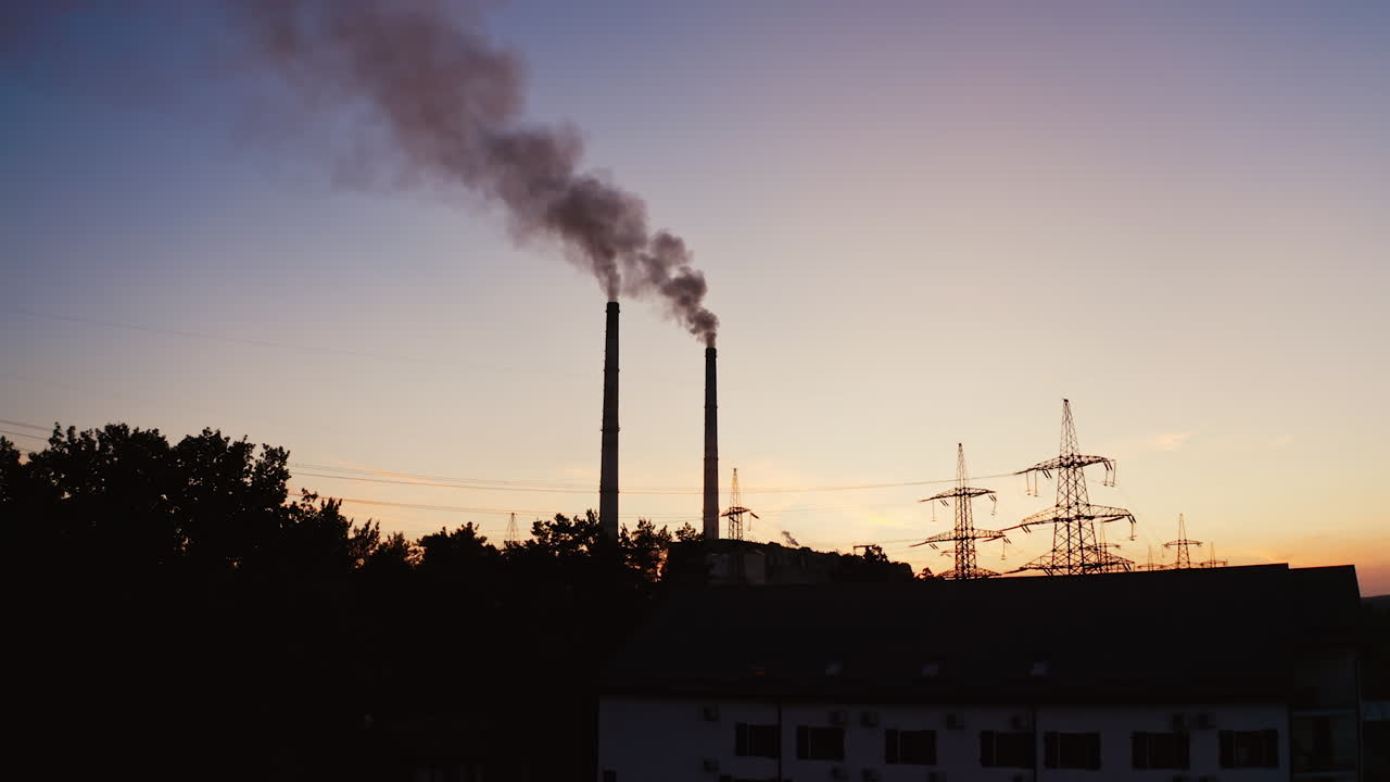 Industrial pipes of the thermal power plant at sunset. Smoke from the factory chimneys against the evening sky. The concept of environmental pollution.