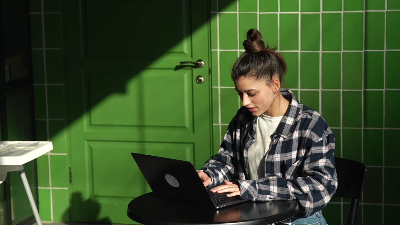 mujer joven trabajando en una computadora portátil en un café