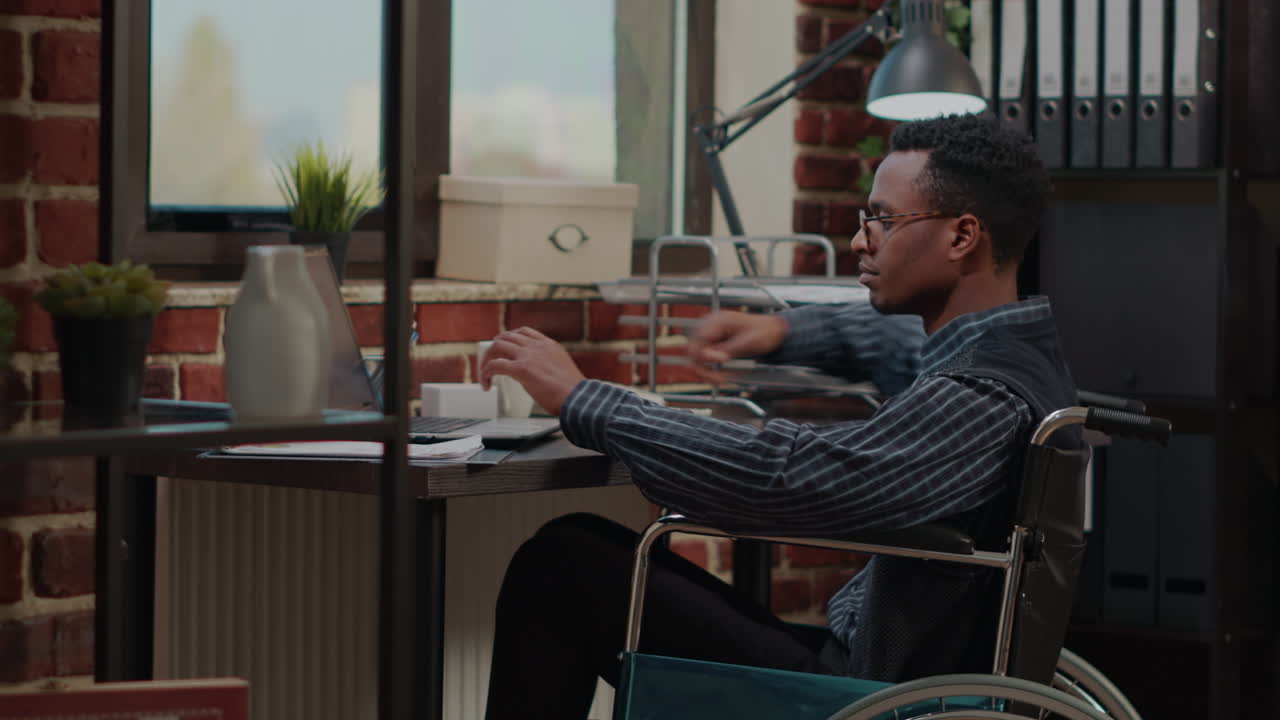 African american man in wheelchair planning sales growth on laptop