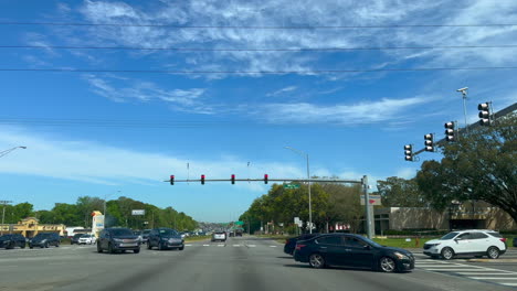 street view of busy 4 way intersection as traffic crosses in front of car turning