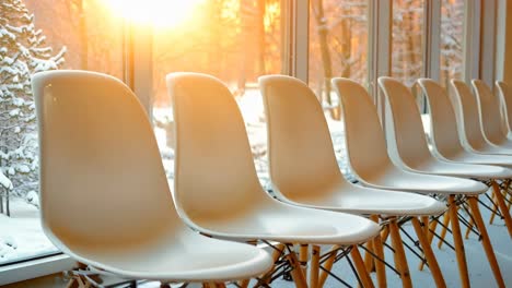 a row of white chairs sitting in front of a window