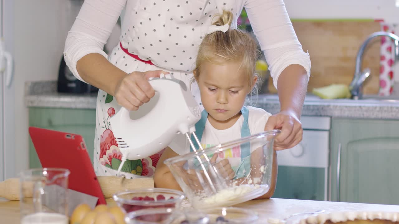 Little girl watching her mother whisking cream