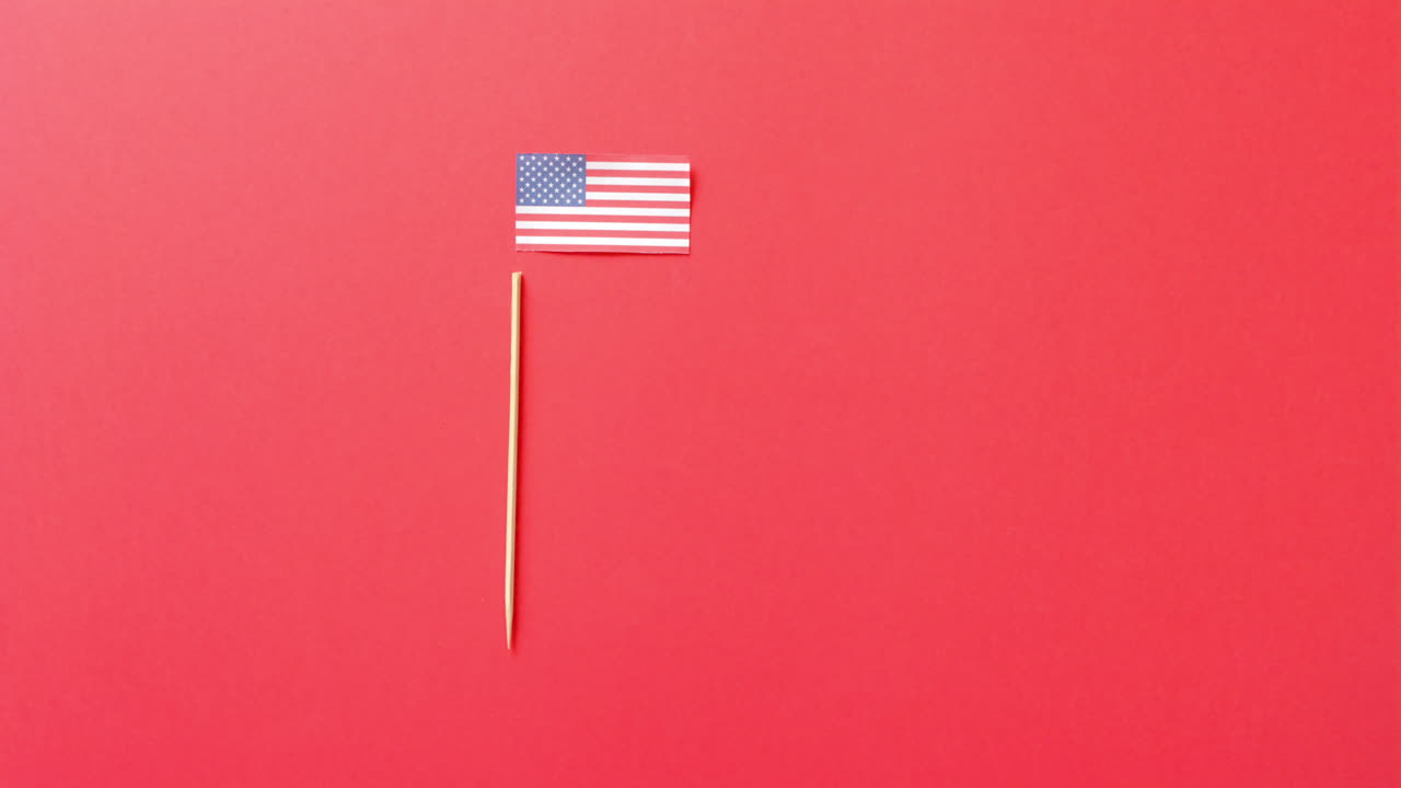 Bandiera nazionale degli Stati Uniti e asta adagiate su sfondo rosso con spazio per il testo.