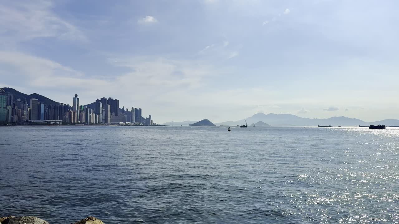 Footage of Hong Kong harbor featuring vibrant blue waters, bustling ships, ferries, and waterfront activity, capturing the city skyline, maritime transport, and scenic coastal energy