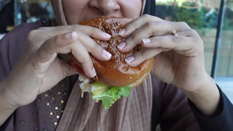 una mujer comiendo una hamburguesa.