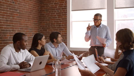 mature businessman standing to address boardroom meeting