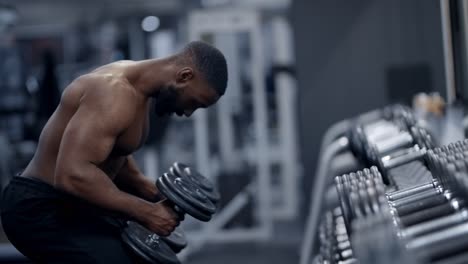athletic african american man picking up dumbbells
