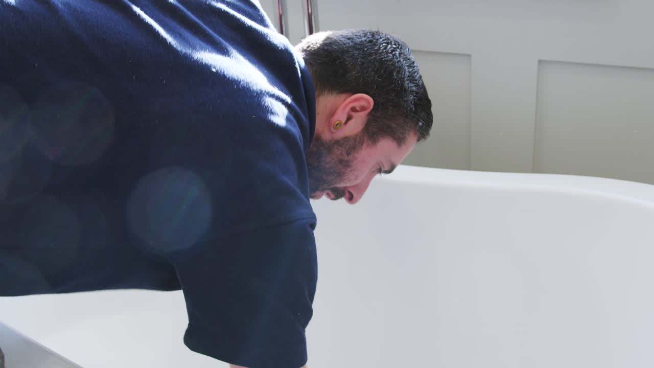 설치 후 자유롭게 서 있는 욕조를 청소하는 배관공