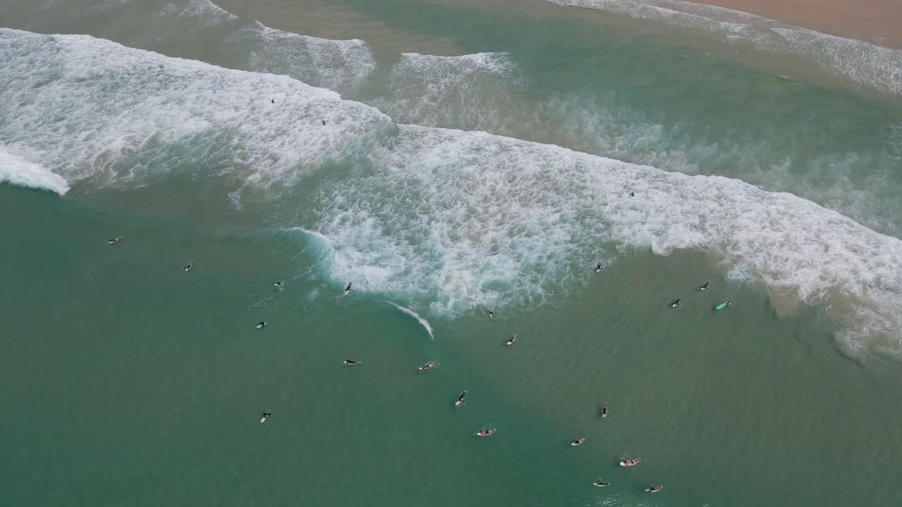 Vista dall'alto dei turisti sulle loro tavole da surf che si godono le onde dell'oceano di Duranbah Beach a Gold Coast, Australia