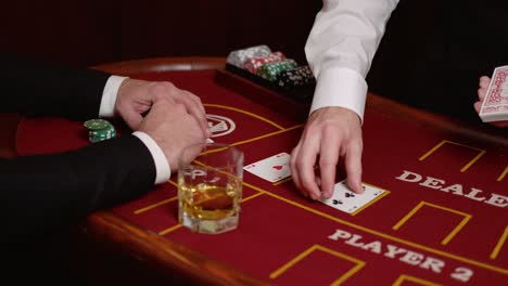 imágenes en cámara lenta de un hombre bebiendo whisky mientras juega al póquer en un casino.