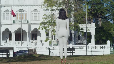 Una-Joven,-Vestida-Con-Un-Traje-Blanco,-Aparece-Fotografiada-En-Una-Ciudad-Caribeña-Con-Castillos-Detrás-De-Ella.