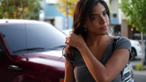 A-beautiful-young-hispanic-woman-standing-on-the-urban-city-street-sidewalk-while-shopping-the-stores-at-sunset-SLOW-MOTION