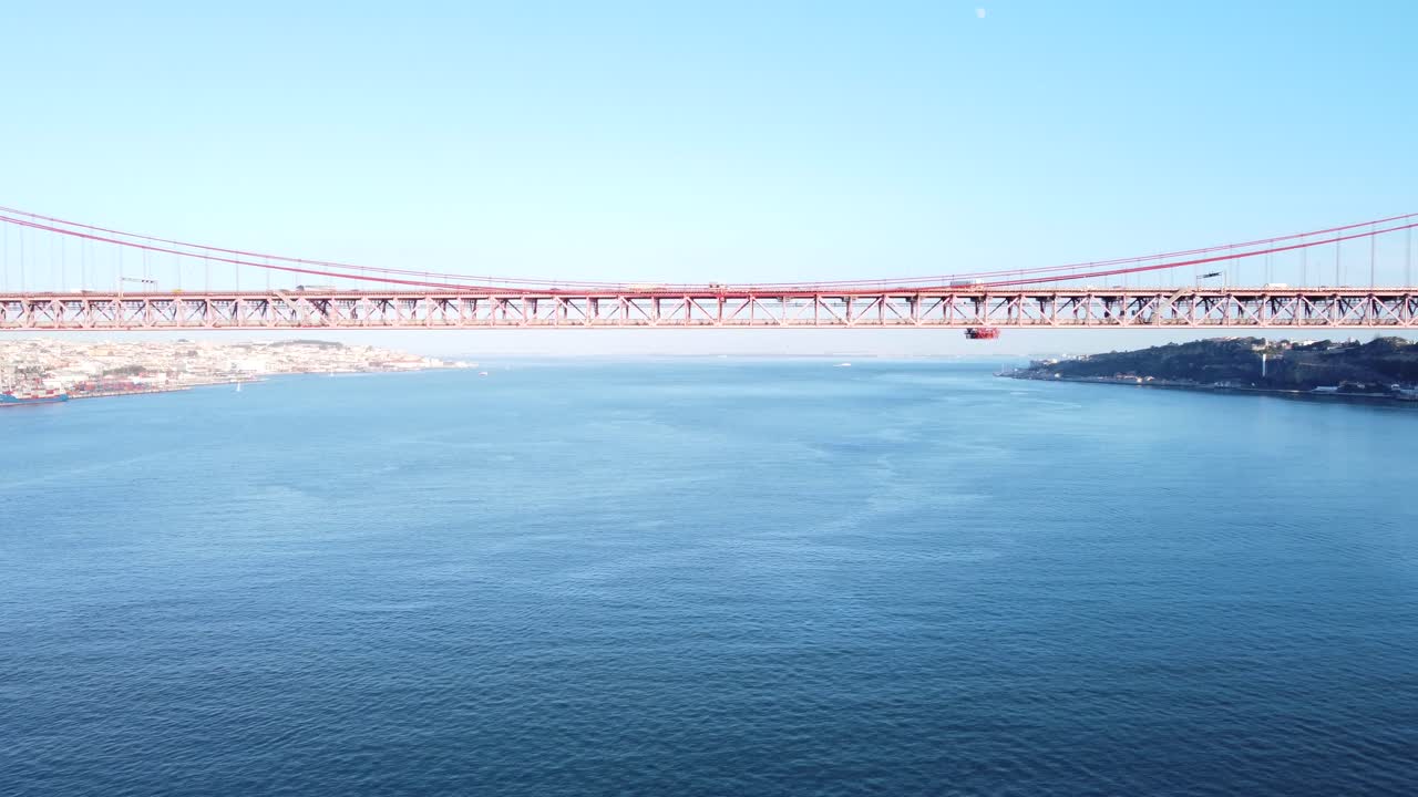 빨간색 현수교가 있는 포르투갈 리스본의 테조(tejo) 위의 멋진 다리 아래를 매우 가깝게 지나는 드론
