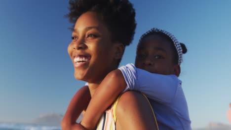 Happy-african-american-couple-carrying-daughter-and-son-on-sunny-beach