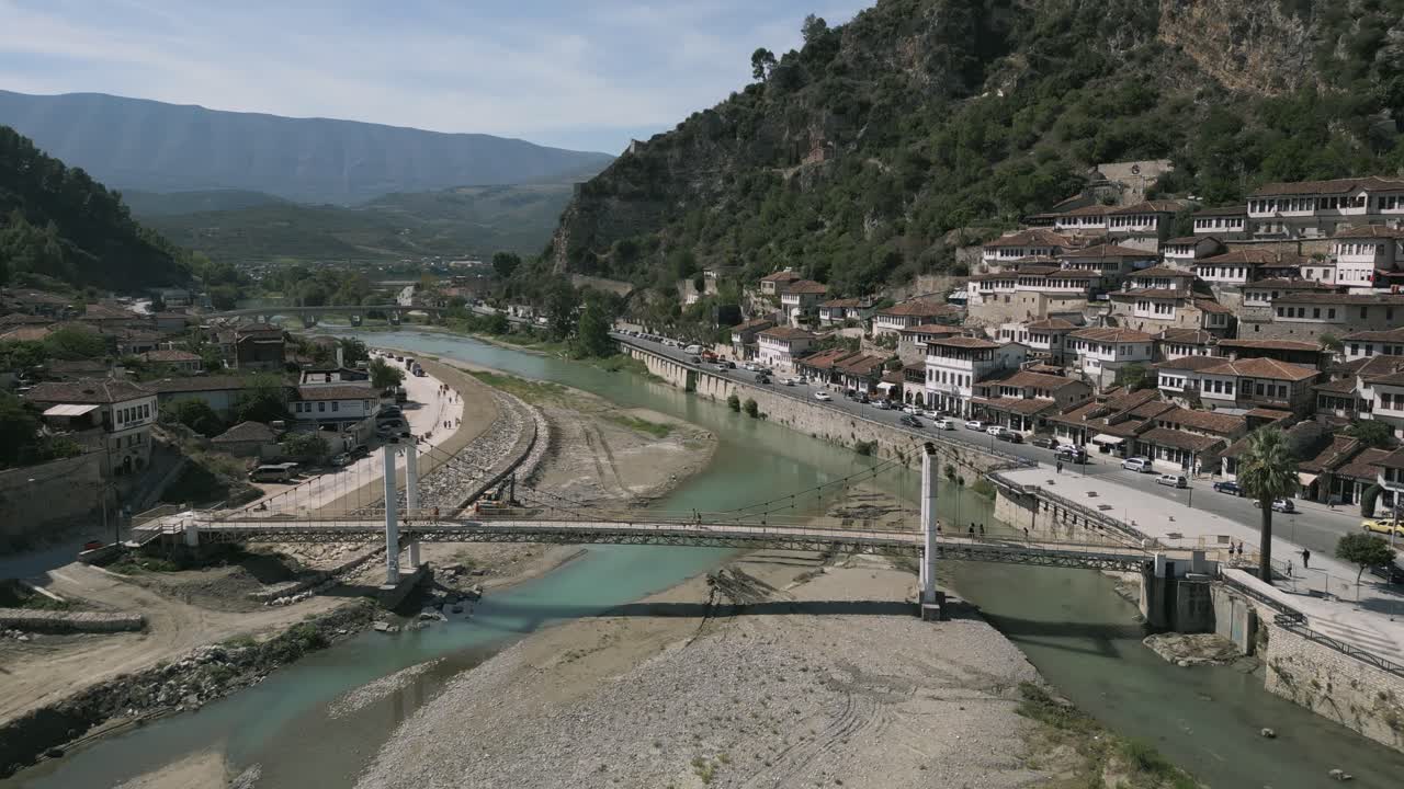 toma aérea de personas moviéndose sobre puentes y casas antiguas además del río en berat, albania