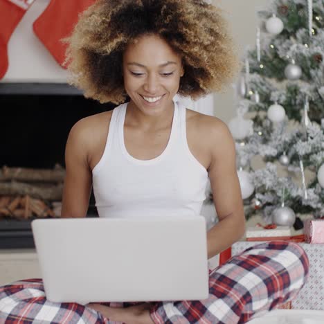 Mujer-Usando-Una-Computadora-Portátil-Frente-Al-árbol-De-Navidad