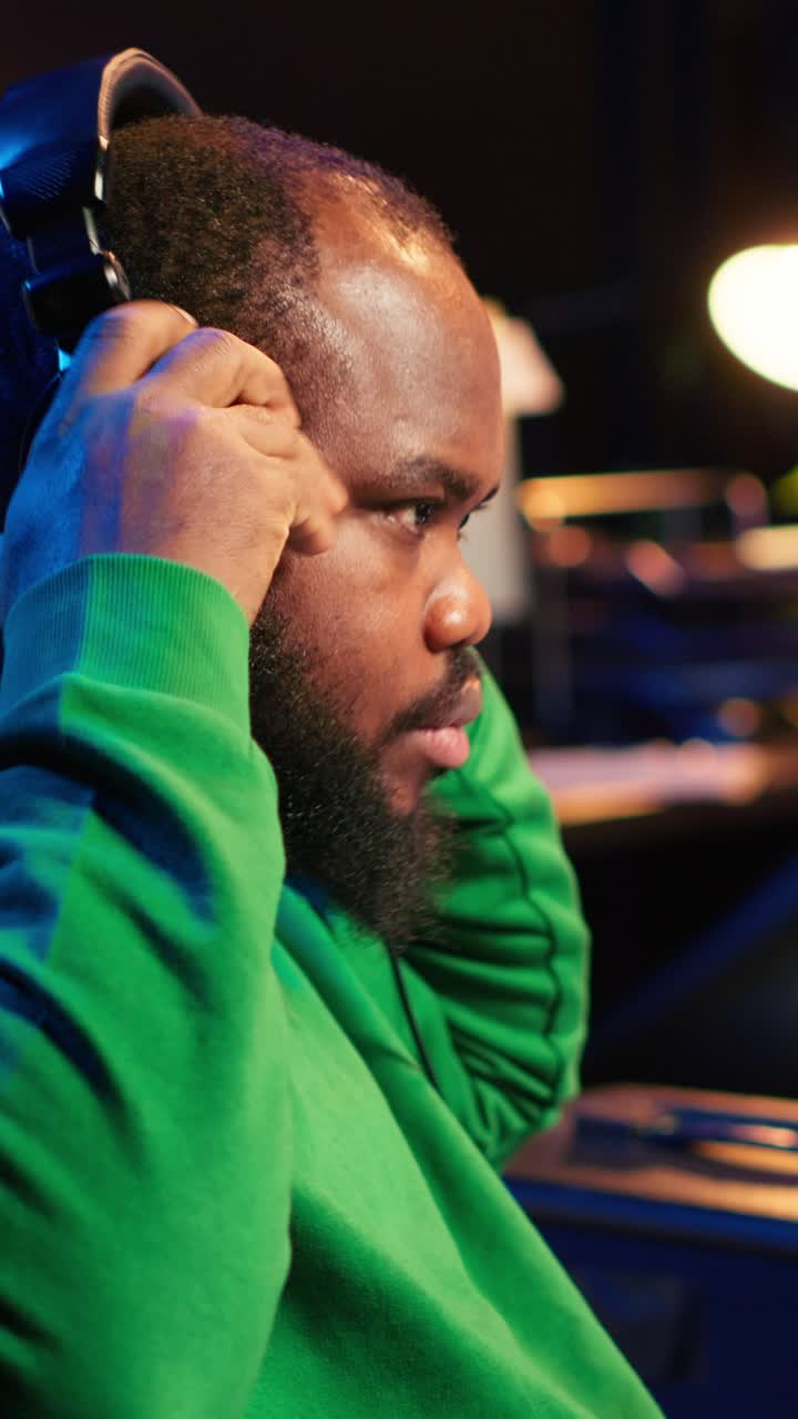 Homme jouant du clavier et mettant un casque dans un studio de musique
