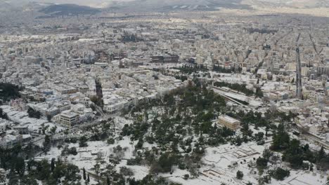 aerial drone view over a park towards snowy cityscape of athens, winter in greece