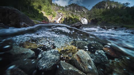an over-under shot of the fast-flowing shallow river with a rocky bottom