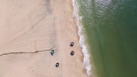 drone forward-moving top-down shot showing fishing boats, sandy shore, and ocean at mui ne beach.