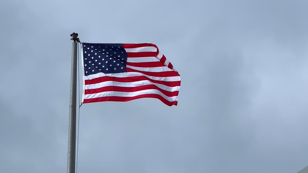 bandera americana de 4k, 60p ondeando en el viento contra un cielo gris brillante