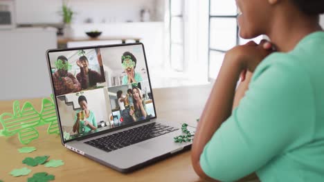 Smiling-diverse-group-of-friends-with-beer-wearing-clover-shape-items-on-video-call-on-laptop