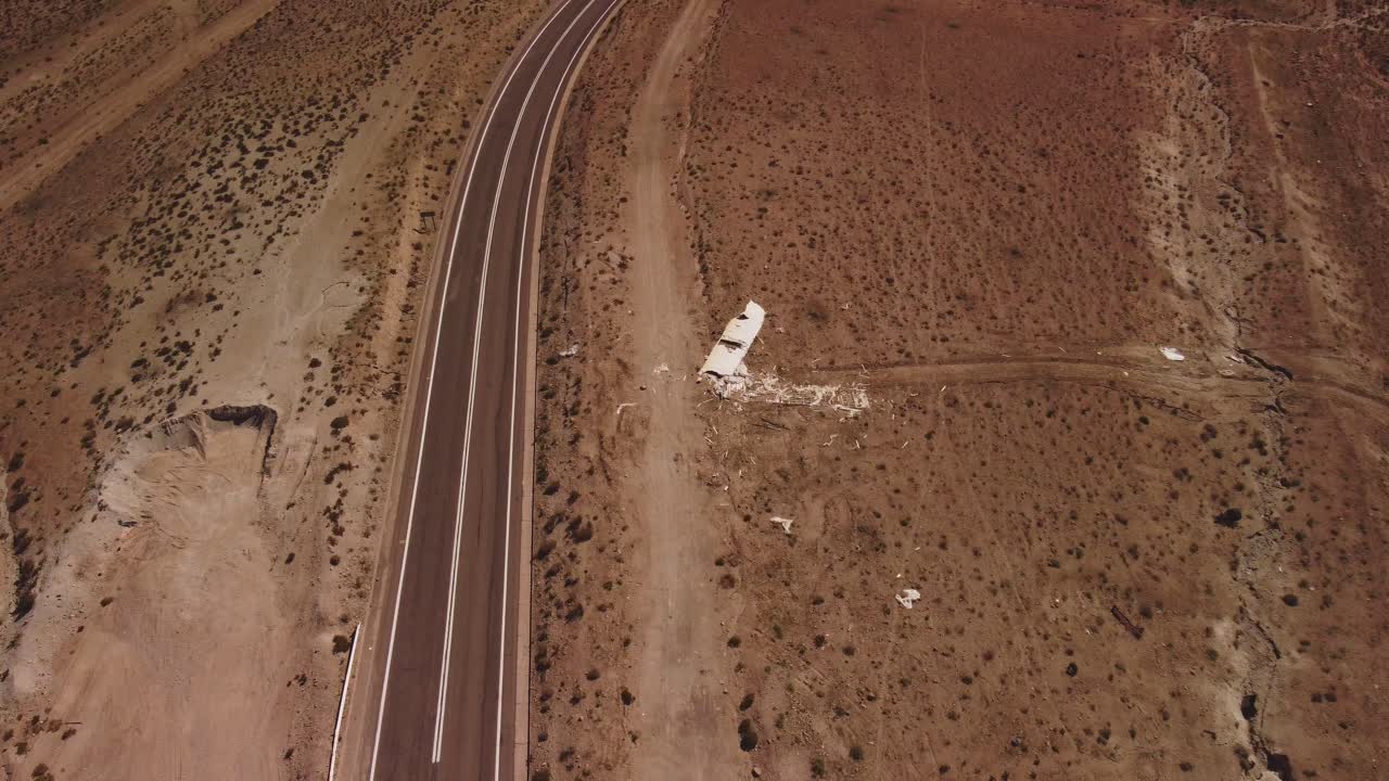 Aerial view of a winding road cutting through the barren Atacama Desert near San Pedro de Atacama, Chile. Arid, remote landscape with mountains in the distance.