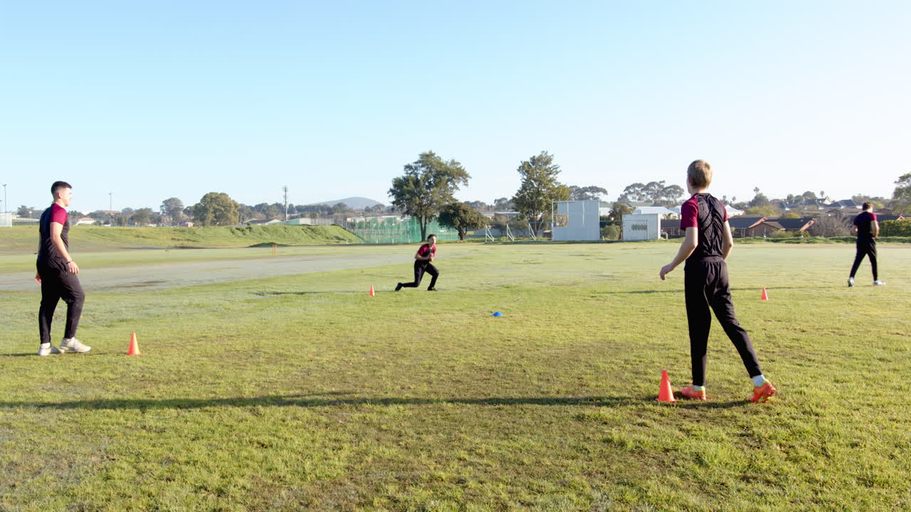 Teams of multiracial male cricket players practicing cricket on pitch