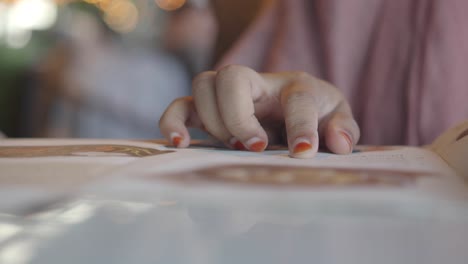 close-up of a person's hand flipping through a menu