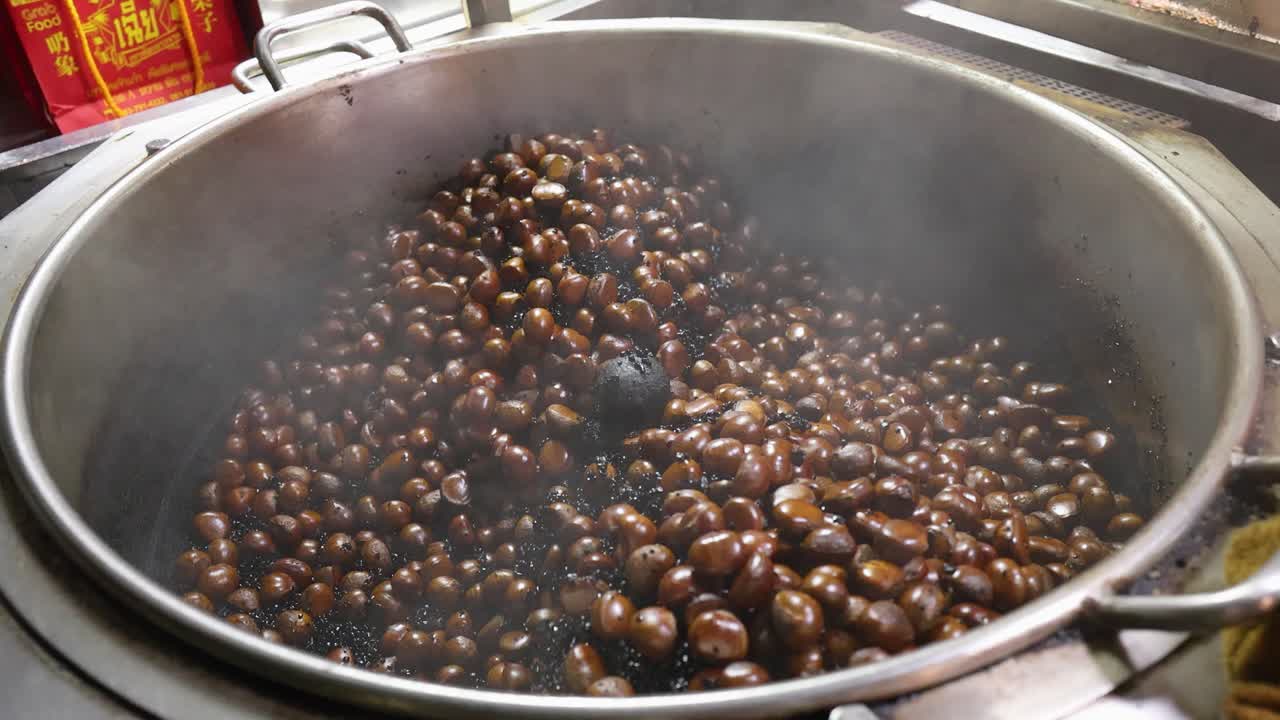 Chestnuts roasting in steaming wok, street food style, Chinatown Bangkok, medium shot, natural lighting