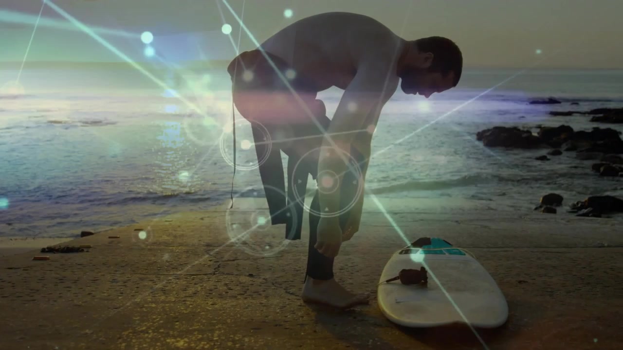 Mens solen går ned, knæler en midaldrende mandlig surfer, fastgør sin leash, gør våddragten klar og forbereder sig på at komme i vandet.