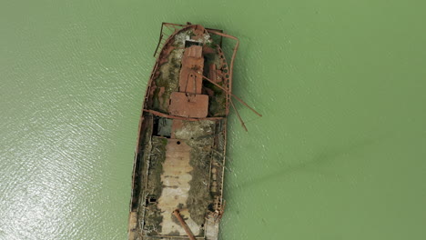 Rostiges-Rotes-Schiffswrack-Steckte-Im-Seichten-Grünen-Wasser-Fest