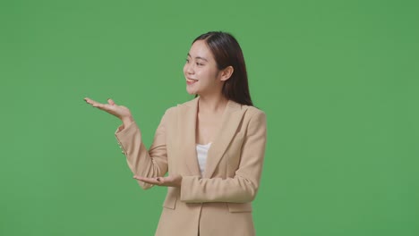 an asian business woman showing open hand palm while standing in the green screen