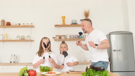 insanely happy dad and two kids are dancing in a modern kitchen with dishes insanely happy dad and two kids are dancing in a modern kitchen with dishes rhythmic movements in the kitchen rhythmic at home