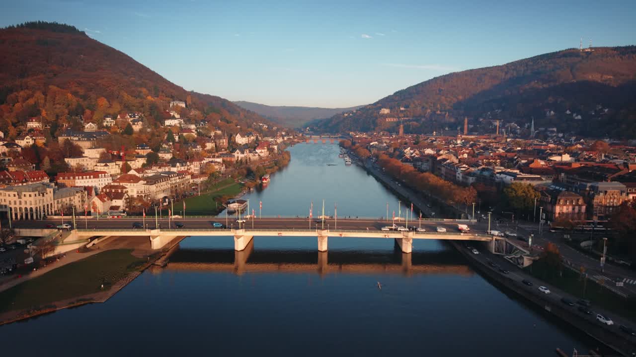 Dronevideo i biografkvalitet af Neckar-dalen og Theodor-Heuss-Brücke i Heidelberg med sporvognstrafik ved solnedgang