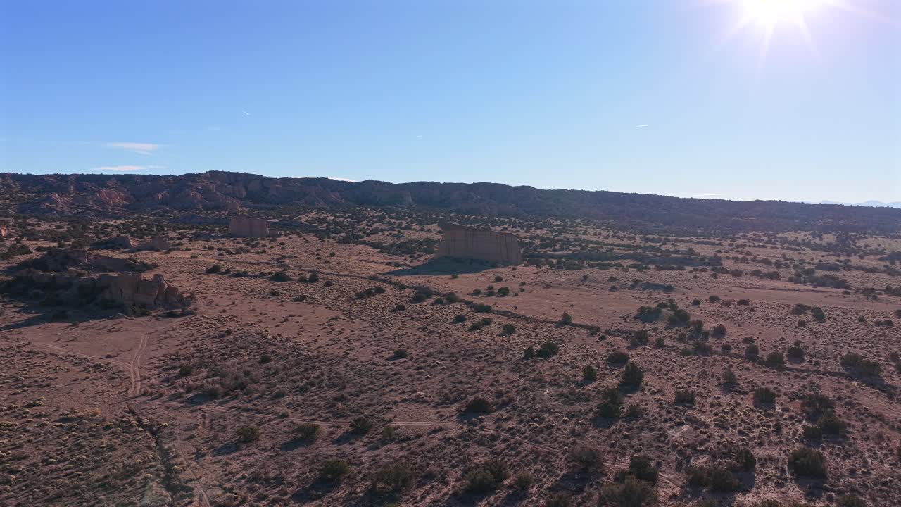 Striking aerial view of two isolated rock monoliths rising from the vast, rugged high desert landscape. The scene captures the unique geology of New Mexico's remote northern region