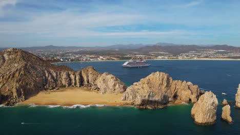 aerial view away from the lovers beach with a cruise liner in the background in cabo san lucas, mexico - pull back, drone shot