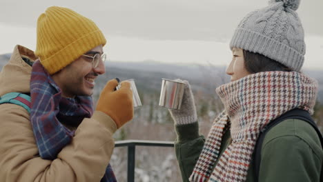 couple enjoying hot drink on snowy mountaintop