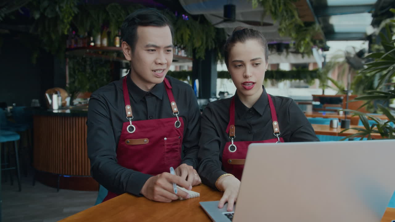 Bi-ethnic Cafe Employees Working on Wireless Laptop