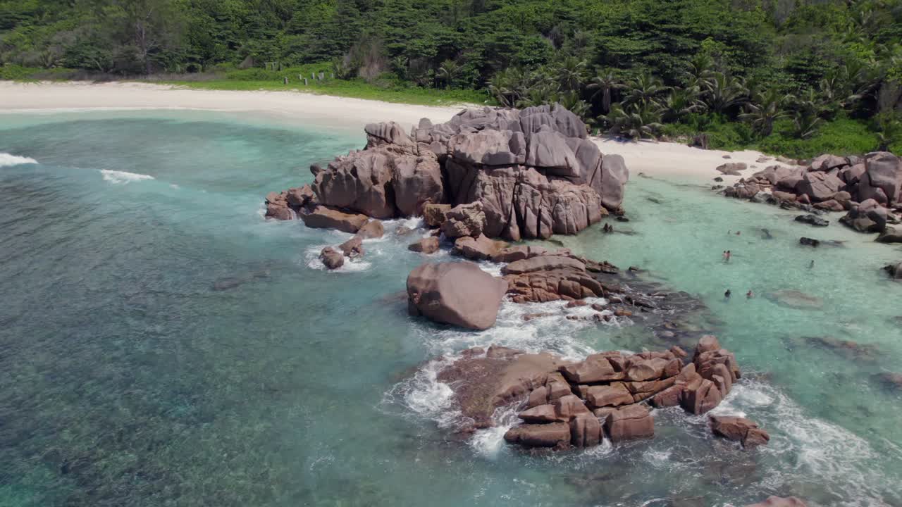 Drone rotatif de gigantesques rochers de granit près du rivage, eau turquoise claire, personnes faisant de la plongée avec tuba, vue sur toute la plage, Anse Cocos, La Digue, Seychelles 004