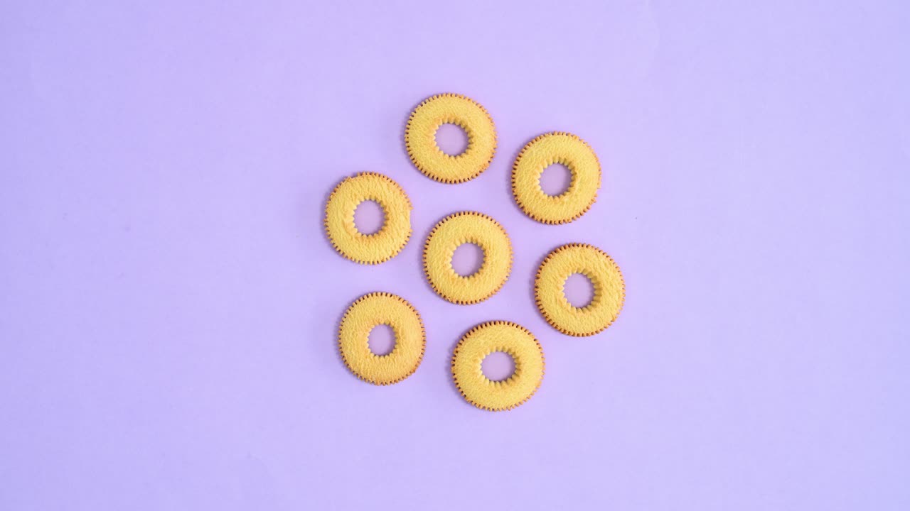 밝은 보라색 배경에 춤추는 둥근 비스 쿠키.