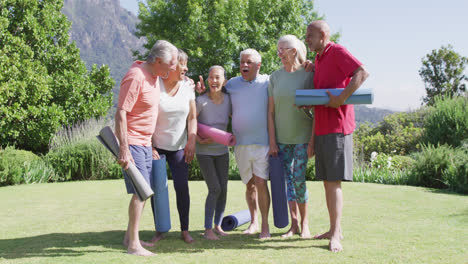 Diverse-group-of-happy-male-and-female-seniors-talking-after-exercising-in-sunny-garden,-slow-motion