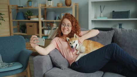 woman taking selfie with her dog on the sofa