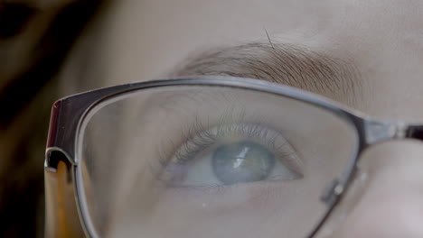 Closeup-on-pretty-blue-eye-and-eyelashes-of-a-young-boy-wearing-glasses-as-he-gazes-upward-with-rack-focus