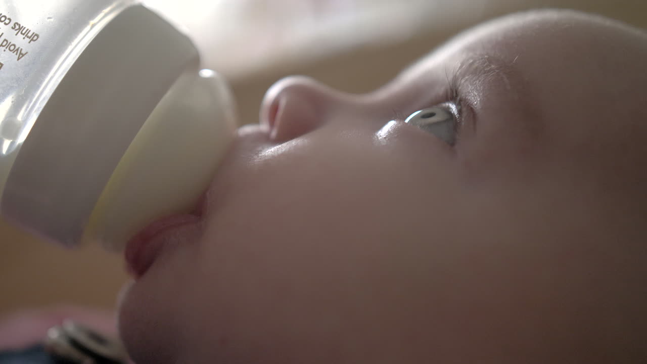 el bebé está bebiendo un poco de leche de una botella mirando hacia arriba, primer plano macro, fullhd 24p apple prores422
