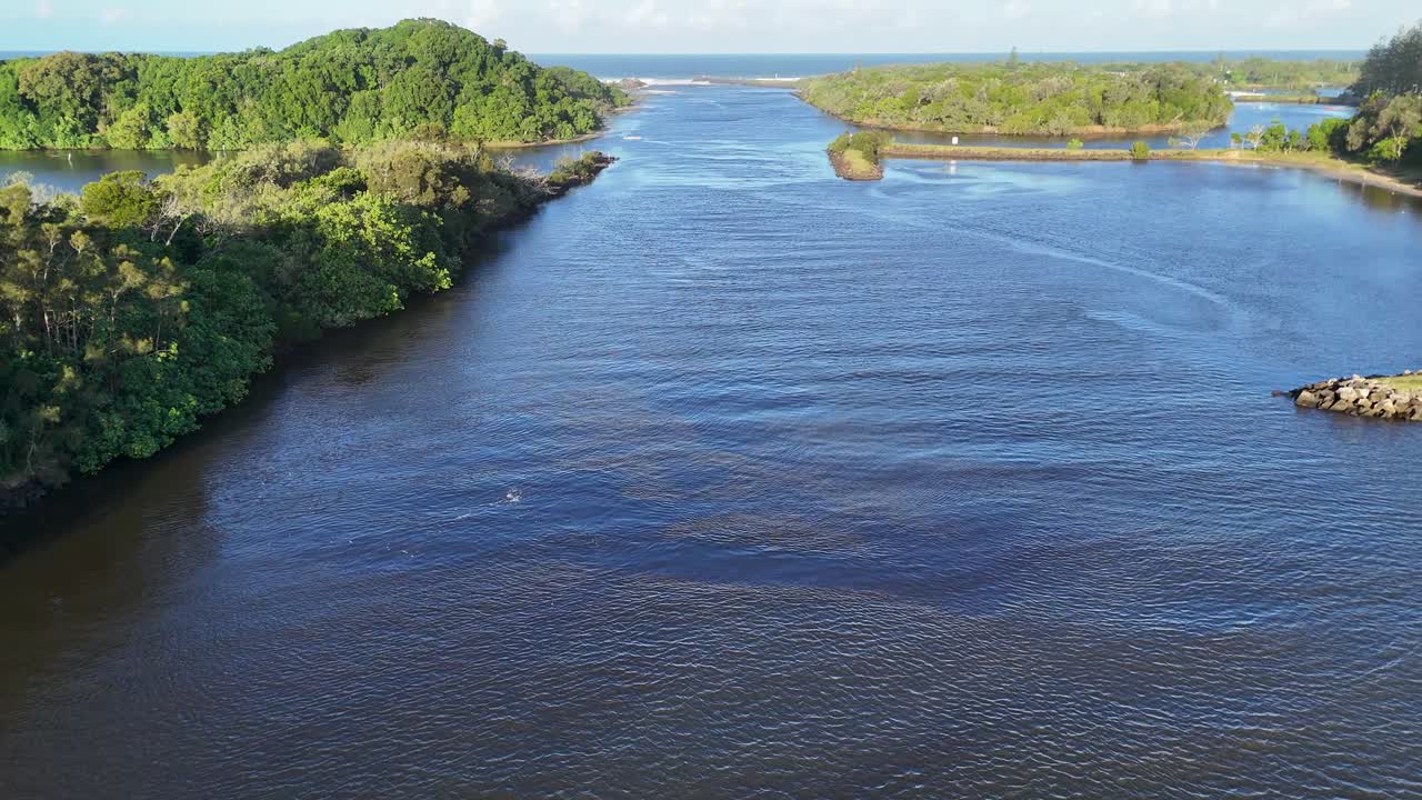 Drone footage captures a serene river landscape with lush greenery and calm waters during sunset