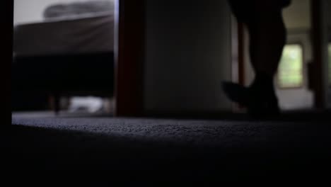 young man in dark hallway approaching the ground level camera, then entering a bedroom and closing the door behind him