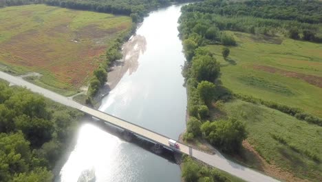 drone aerial view following iowa river water trail with highway bride at hills iowa